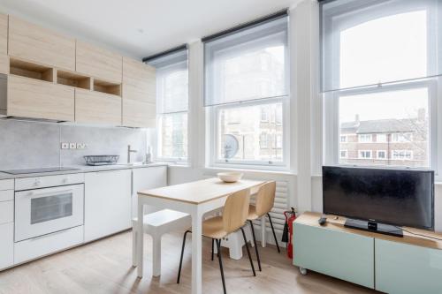 a kitchen with white cabinets and a table with chairs at Live like a Londoner by TOWER BRIDGE in London