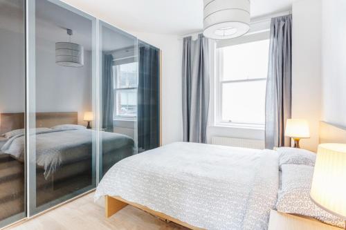 een slaapkamer met een bed en een grote spiegel bij Live like a Londoner by TOWER BRIDGE in Londen