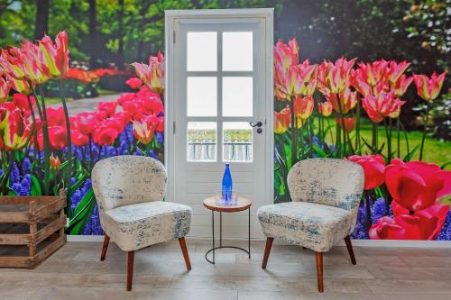 two chairs and a table in front of a painting of flowers at Wellness Bed & Breakfast Pergamo in Voorhout
