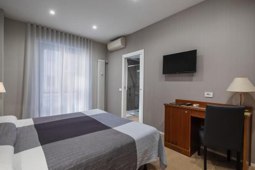a bedroom with a bed and a desk and a television at Hotel Excelsior Pavia in Pavia