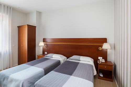 a hotel room with two beds and two lamps at Hotel Excelsior Pavia in Pavia