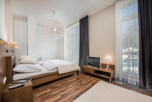 Schlafzimmer mit einem Bett, einem TV und einem Kronleuchter in der Unterkunft Family Apartment, Apartment House Oliver in Štrbské Pleso