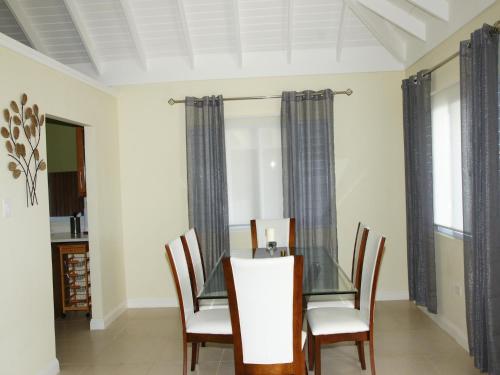 a dining room with a glass table and chairs at Jamnick Vacation Rentals - Fern Court, Richmond Estate, St Ann, Jamaica in Ocho Rios