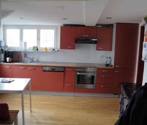 a kitchen with red cabinets and a white counter top at Rheintal-Zimmer in Altstätten