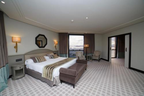 a bedroom with a bed and a couch and a table at Hotel Bahía in Santander
