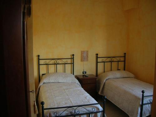 2 letti in una camera da letto con pareti gialle di La Dolce Sosta a Pietrelcina