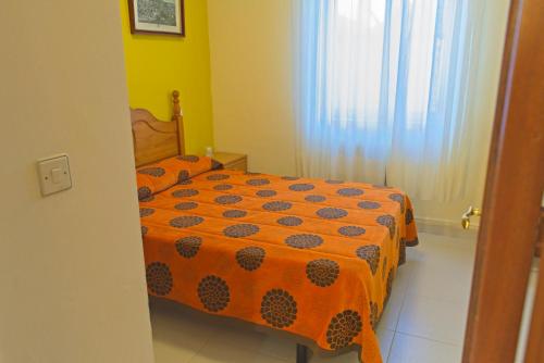 - une chambre avec un lit et une couette en orange dans l'établissement Casa Rural El Negrillo, à Ricobayo