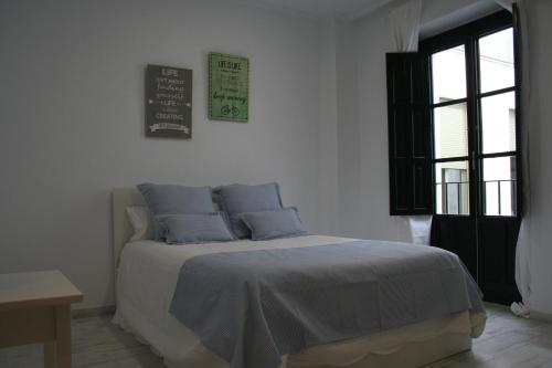 Dormitorio blanco con cama con almohadas azules en CLB Sierpes Apartment en Sevilla