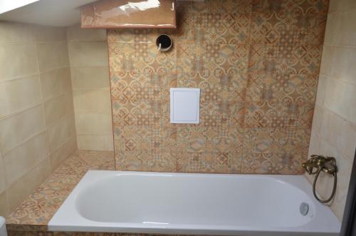 a bathroom with a tub and a tile wall at Ashram Hotel in Primorsko