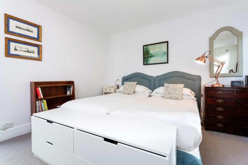 a bedroom with a large white bed and a dresser at Veeve - A Kensington Mews in London
