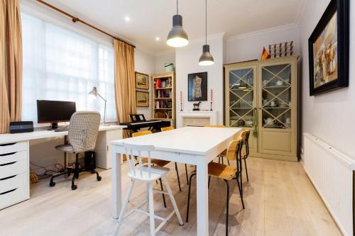 een kantoor met een witte tafel en stoelen en een bureau bij Veeve - A Kensington Mews in Londen