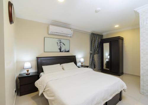 a bedroom with a large white bed and two lamps at Eastren Front in Al Khobar