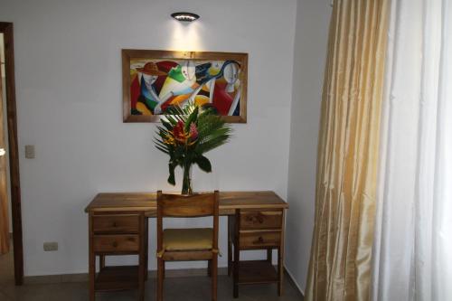 a table with a vase of flowers and a painting at Albachiara Hotel - Las Terrenas in Las Terrenas