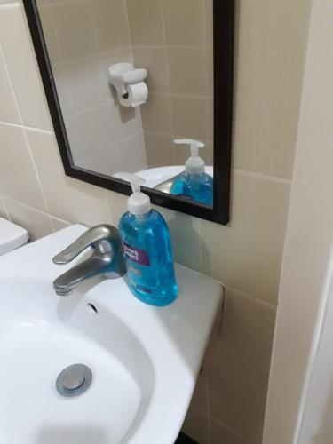 a blue bottle of soap on a sink in a bathroom at HappyNest Couple room DF in Tagaytay