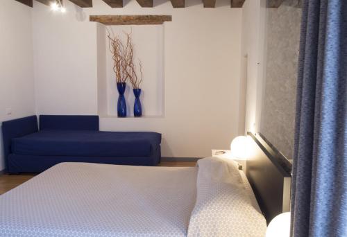 a bedroom with a bed and a blue couch at Ristolocanda Grani Di Pepe in Flaibano