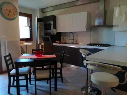 a kitchen with a table and some chairs and a clock at Casa Felicité - di Francesca e Antonio in Valmareno