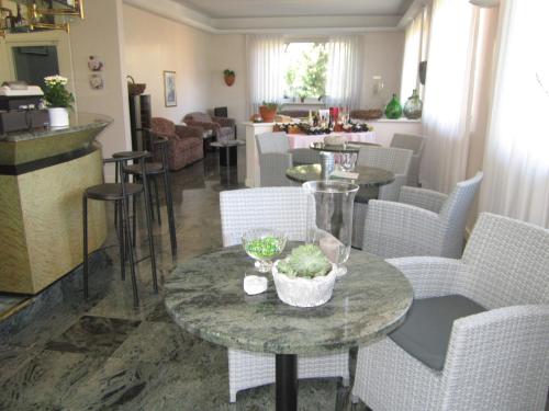 a living room with tables and chairs and a kitchen at Hotel La Villa in Gravedona