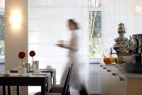 Una mujer camina por una cocina con una mesa. en Hotel Maximilians, en Essen