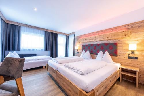 una habitación de hotel con 2 camas y una silla en Hotel Garni Siegmundshof - inclusive Joker Card im Sommer, en Saalbach Hinterglemm