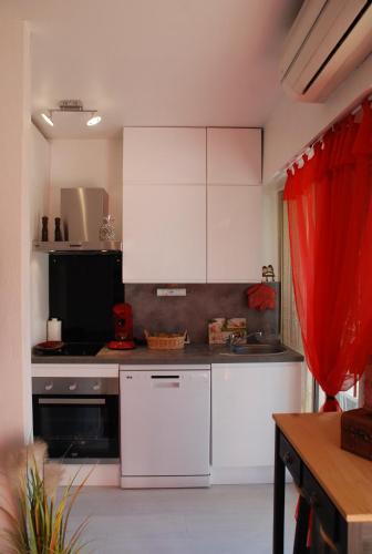 - une cuisine avec des appareils blancs et un rideau rouge dans l'établissement Studio - Juan les pins - proximité plages, à Antibes