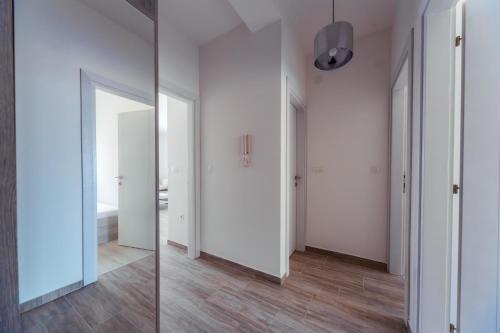 - un couloir avec des murs blancs, du parquet et un miroir dans l'établissement Belvedere Apartments, à Petrovac na Moru
