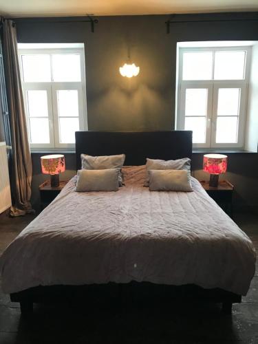a bedroom with a large bed with two lamps at B&B Aux Quatre Bonniers in Olne