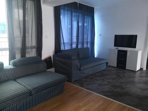 een woonkamer met een bank, een stoel en een televisie bij Blue Bay Palace Apart Complex in Pomorie