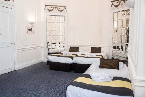 eine Reihe von 4 Betten in einem Zimmer in der Unterkunft Rose Court Hotel in London