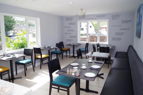 una sala da pranzo con tavoli, sedie e finestre di Strathassynt Guest House a Glencoe