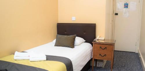 ein kleines Schlafzimmer mit einem Bett und einem Nachttisch in der Unterkunft Rose Court Hotel in London