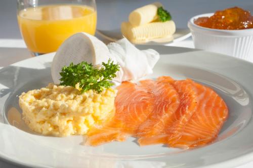 a plate of food with salmon and mashed potatoes and orange juice at Langrish House in Petersfield