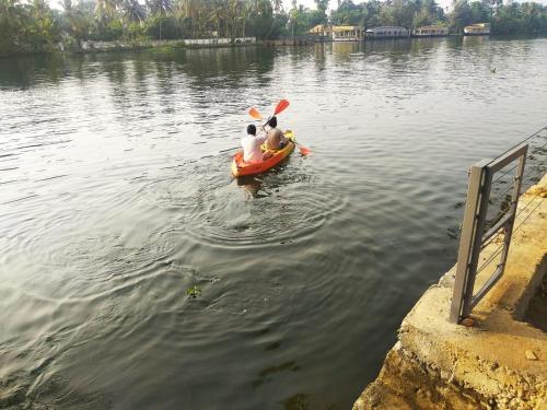 two people in a paddle boat in the water at Water's Edge Villas in Alleppey