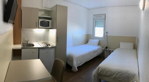 a small room with two beds and a kitchen at Be Myhôtel in Évreux