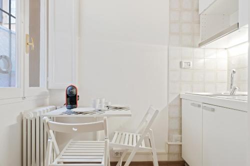 - une cuisine blanche avec une table et deux chaises dans l'établissement Sognando Bologna Flat, à Bologne