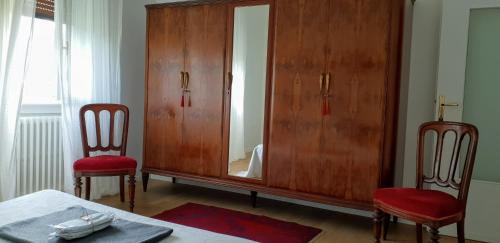 a bedroom with a large wooden cabinet and two chairs at La Turr de Mezz- Bellagio LCA in Bellagio