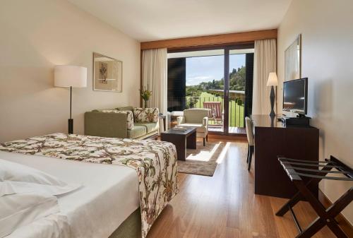a hotel room with a bed, television and a desk at Quinta da Casa Branca in Funchal