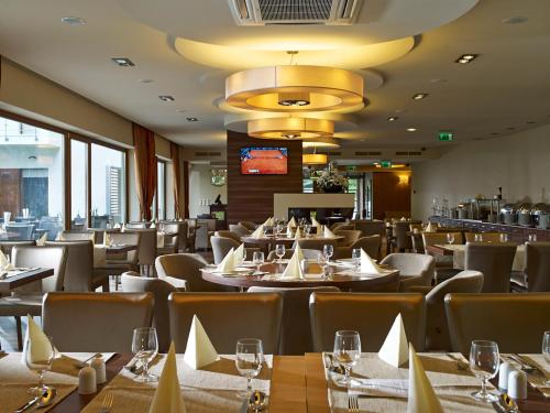 a dining room with tables and chairs and windows at Barack Thermal Hotel and Spa in Tiszakécske