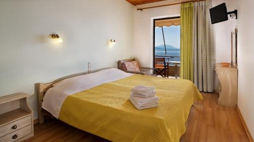 a bedroom with a bed with yellow sheets and a window at Pharos Rooms in Ilia