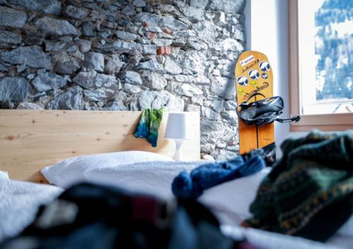 a bedroom with a bed and a skateboard next to a stone wall at Bed&Bike Tremola San Gottardo in Airolo
