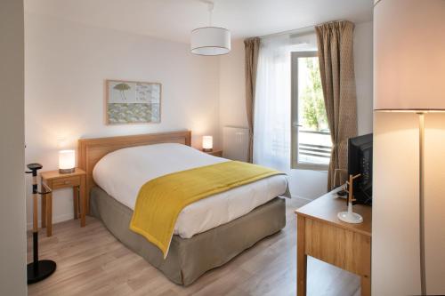 a bedroom with a large bed and a television at DOMITYS L'AIGRETTE BLEUE in Abbeville