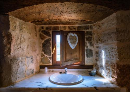 Baño de piedra con lavabo y ventana en Hotel Posada Fuentes Carrionas, en Camasobres