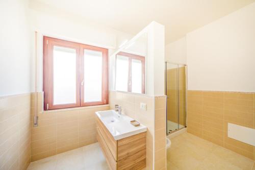 ein Bad mit einem Waschbecken, einer Dusche und einem Spiegel in der Unterkunft Domus Iose Seaview Apartment in Syrakus