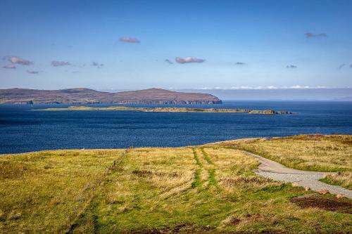 a field of grass next to a body of water at Oran Na Mara, Waternish in Hallin