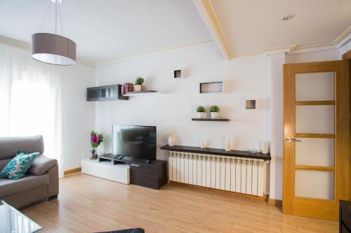 sala de estar con sofá y TV en Apartamentos Abula, en Ávila