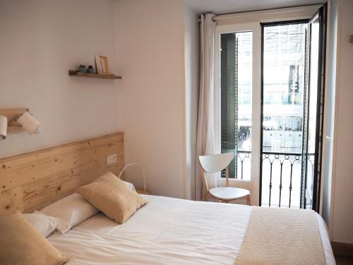 a bedroom with a white bed and a balcony at Pensión Urkia in Donostia-San Sebastián