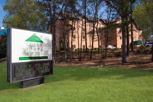 a sign in the grass in front of a building at Guest Inn & Suites - Midtown Medical Center in Little Rock