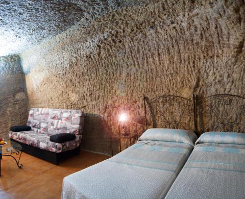 a bedroom with two beds and a couch and a wall at Hostal Batato in Vejer de la Frontera