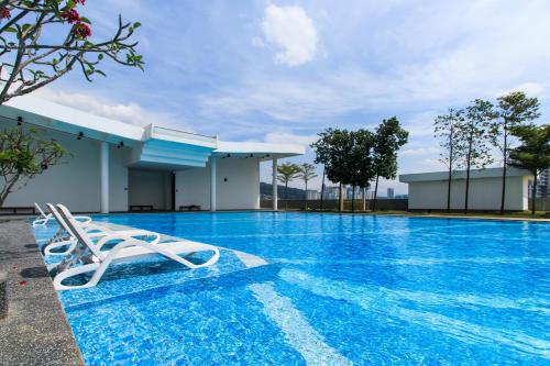 a pool with a lounge chair in front of a building at Encorp Strand Residences by Airhost in Kota Damansara