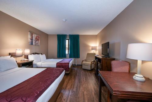 a hotel room with two beds and a flat screen tv at Guest Inn & Suites - Midtown Medical Center in Little Rock