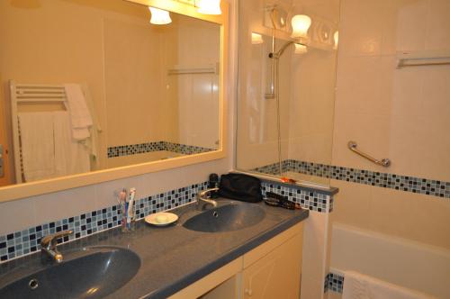 ein Badezimmer mit zwei Waschbecken, einem Spiegel und einer Dusche in der Unterkunft Inter-Résidences Heliotel Marine in Saint-Laurent-du-Var